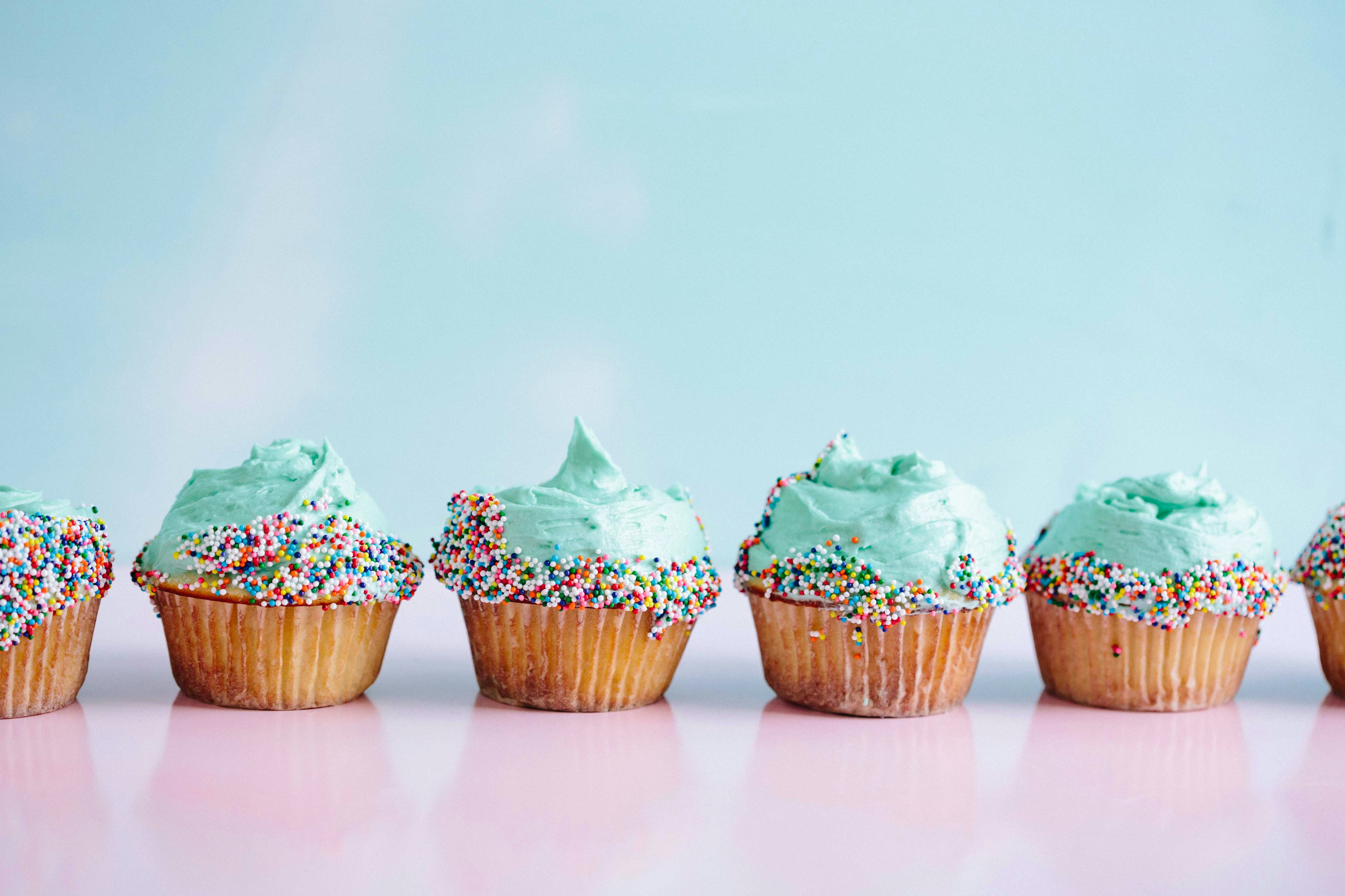 Image of cupcakes in a line, with sprinkles and blue frosting